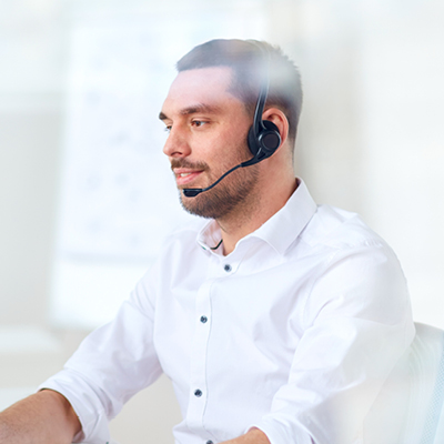 man wearing a white longsleeve with a headset working on a computer